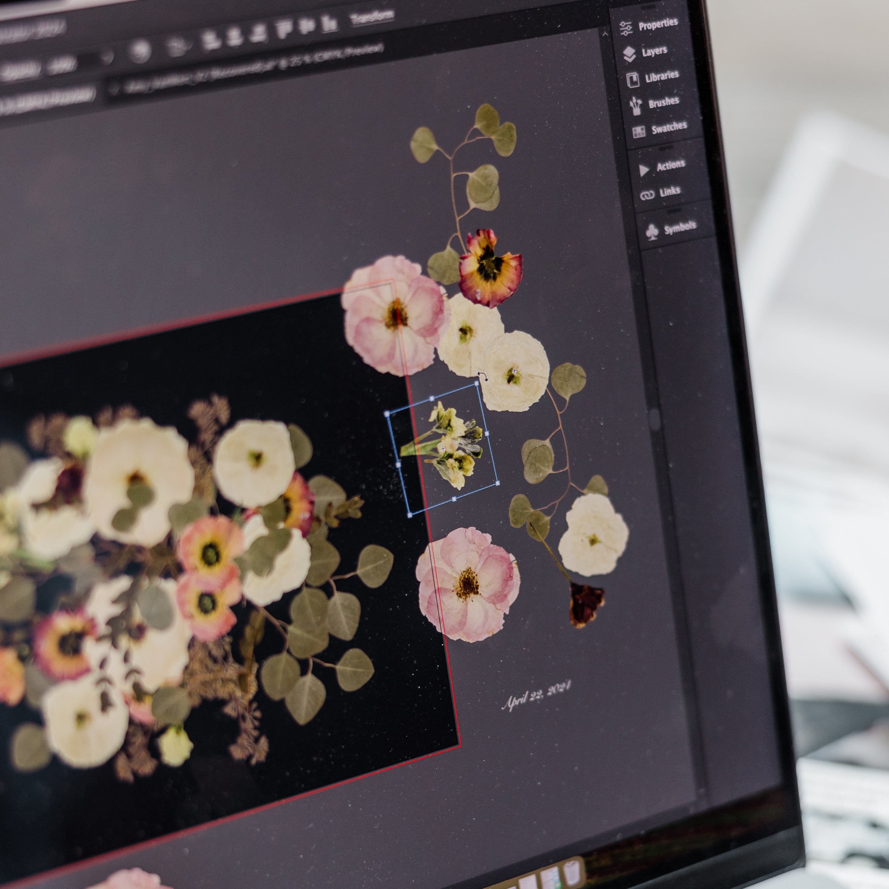 A laptop screen with pressed flowers that are digitized being moved around to create a floral design.