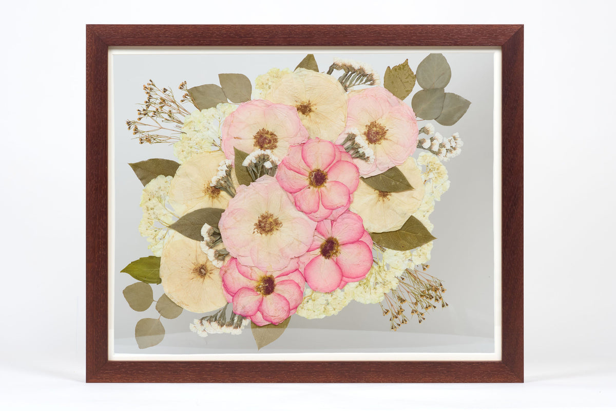 a large walnut colored frame with pink and white pressed florals