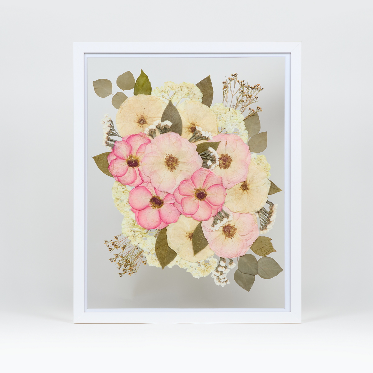A pressed bridal bouquet in a white wood floating frame featuring pressed pink and white florals.