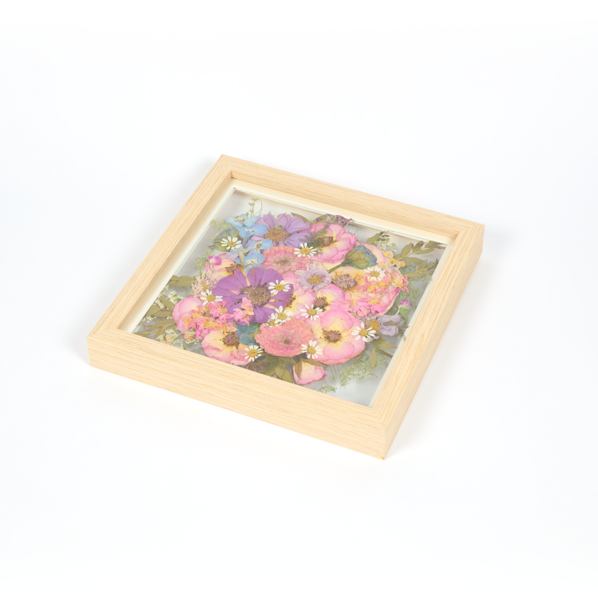 Wedding bouquet preservation frame in a 10x10 size with natural wood surround. All bright pink, blue, and purple pressed florals featuring burst design style.