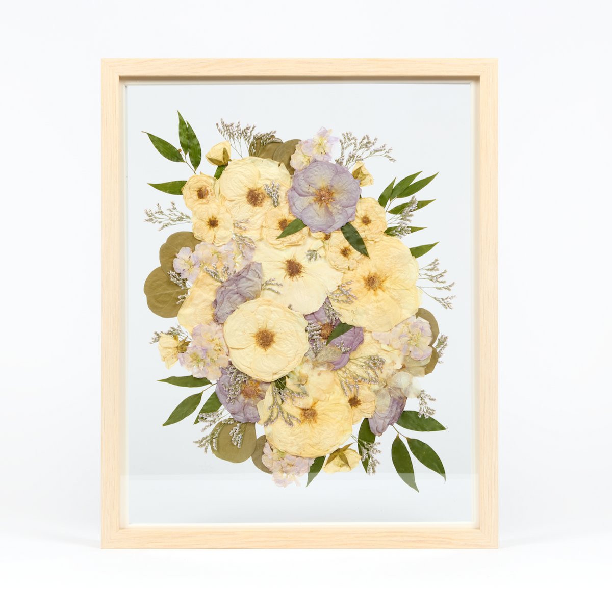 Bridal bouquet preservation in a 16x20 natural wood frame. White and purple pressed florals with greenery accents fill the frame with a floating glass background.