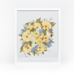 A pressed bridal bouquet in a white wood floating frame featuring pressed blue and white florals.