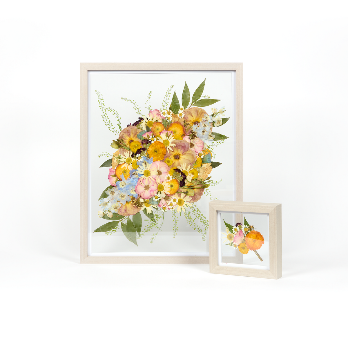 A wedding bouquet preservation set in grey wood with orange, blue, and pink pressed florals.