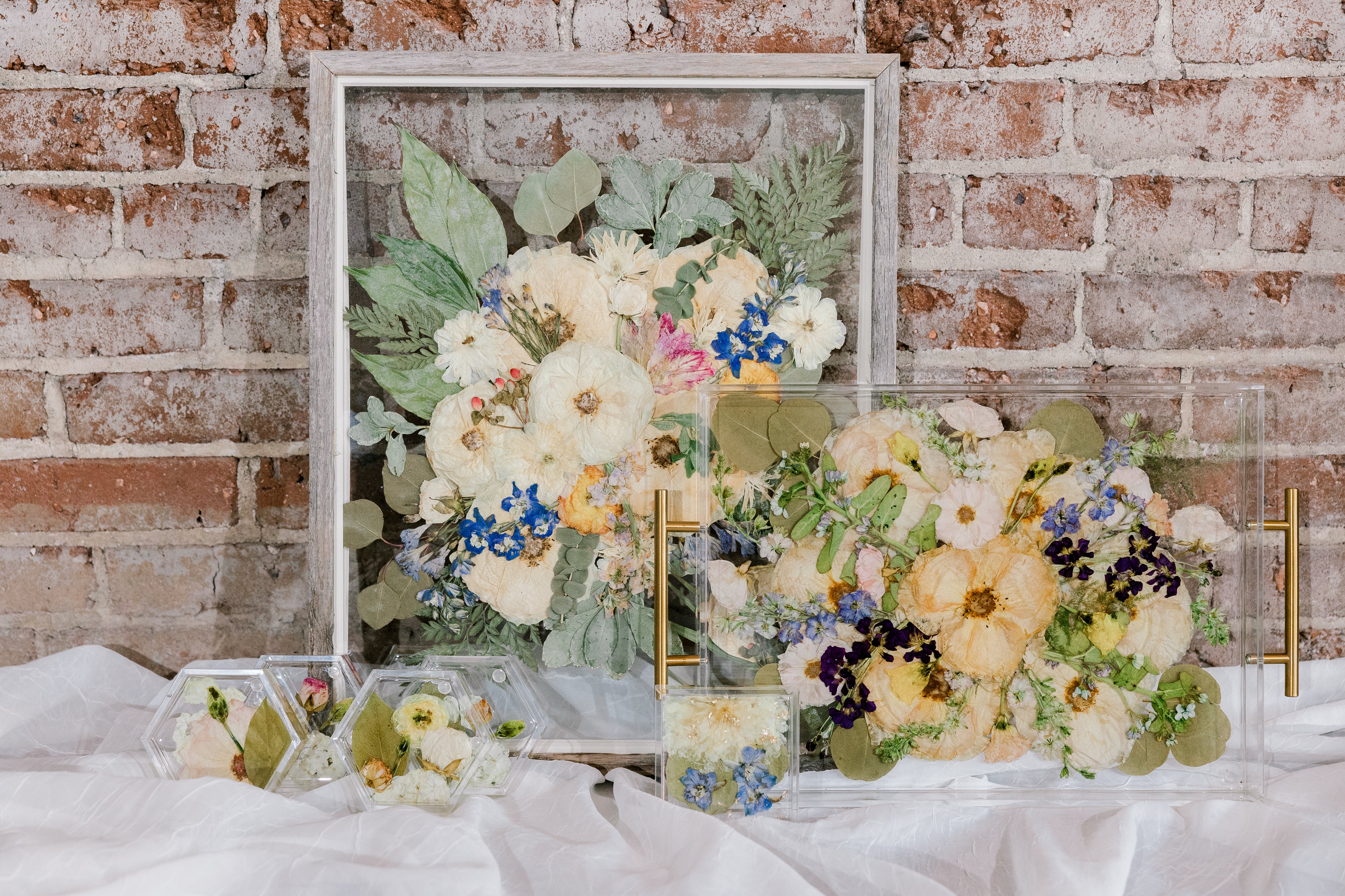 The Works bouquet preservation bundle with a pressed flower frame, a preserved flower serving tray, resin flower coasters, and a resin flower ring dish created by Element Preservation, previously known as Pressed Bouquet Shop.