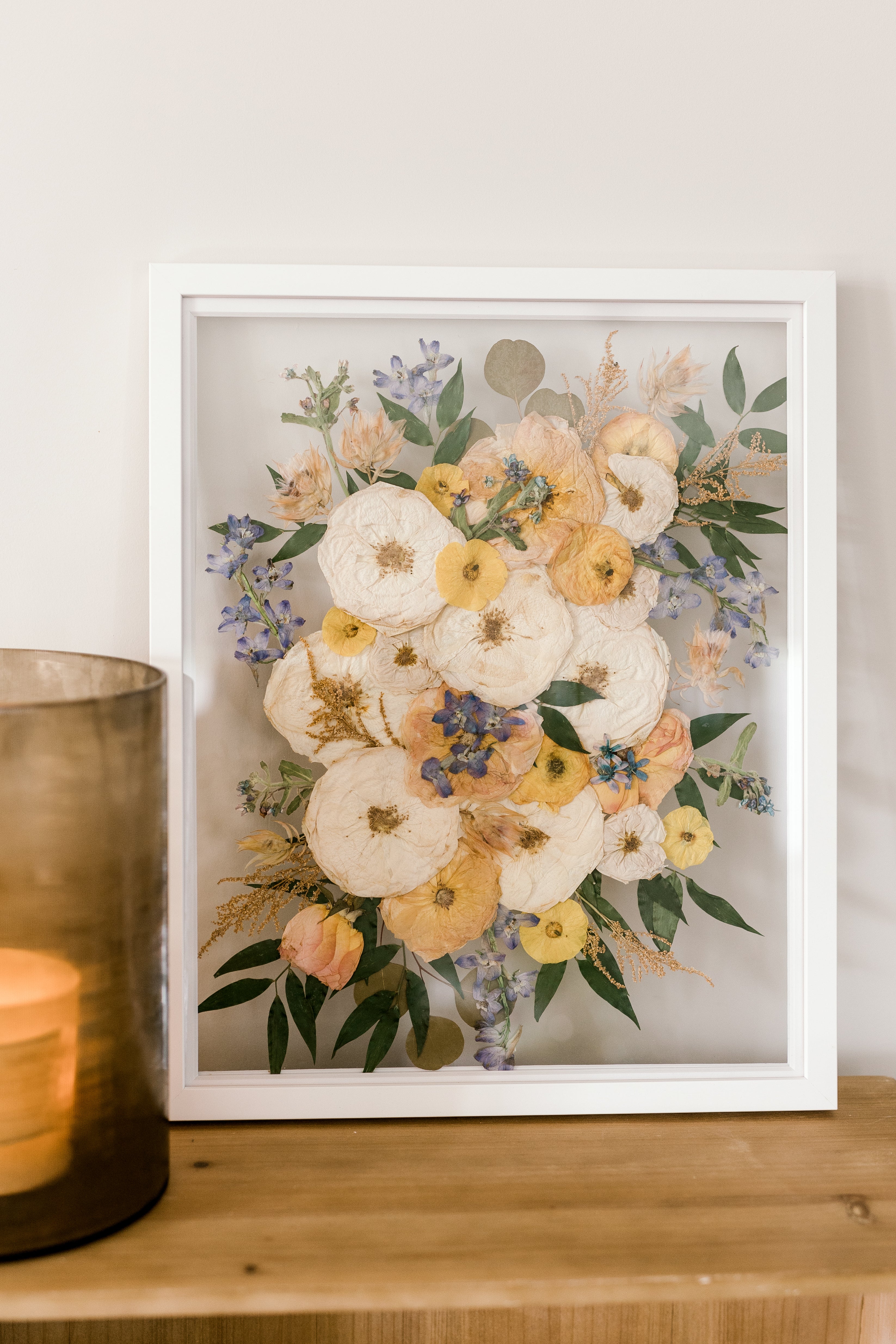 Pressed flowers in a white floating frame made by Element, previously known as the Pressed Bouquet Shop.