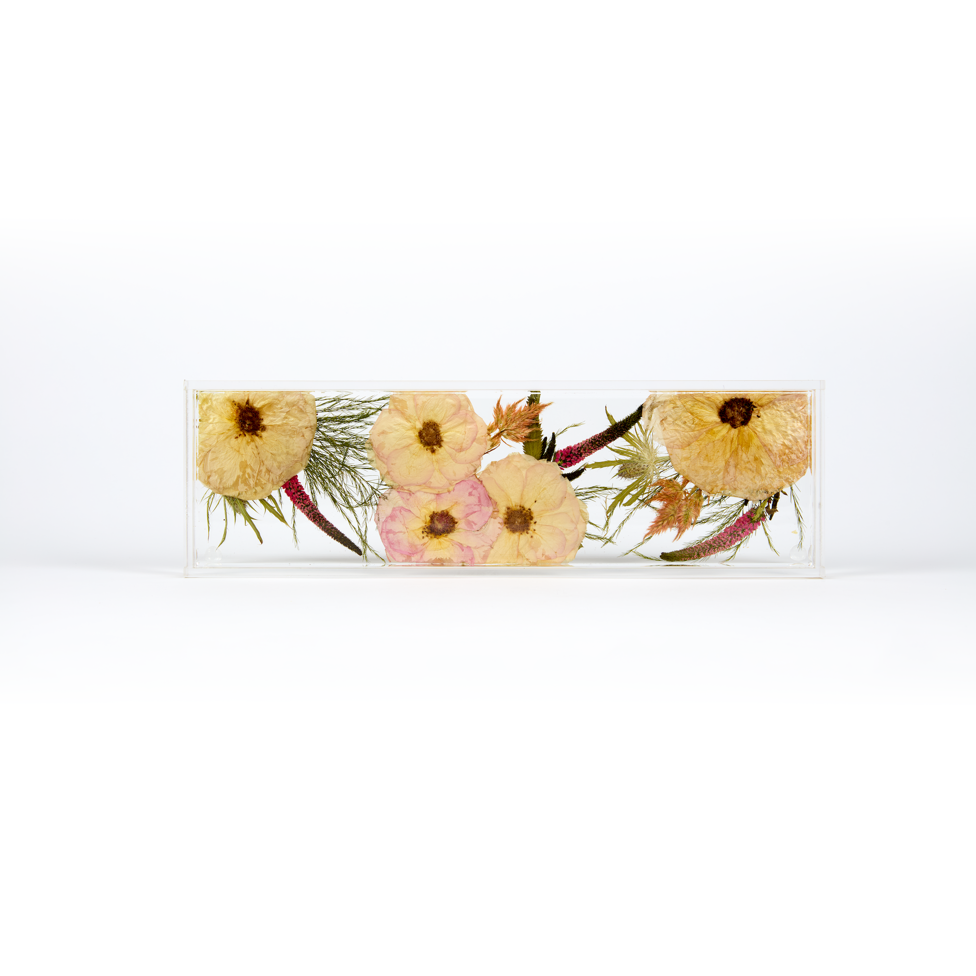 A delicate design of pink and coral pressed florals in a resin display tray as a part of a wedding bouquet preservation order.