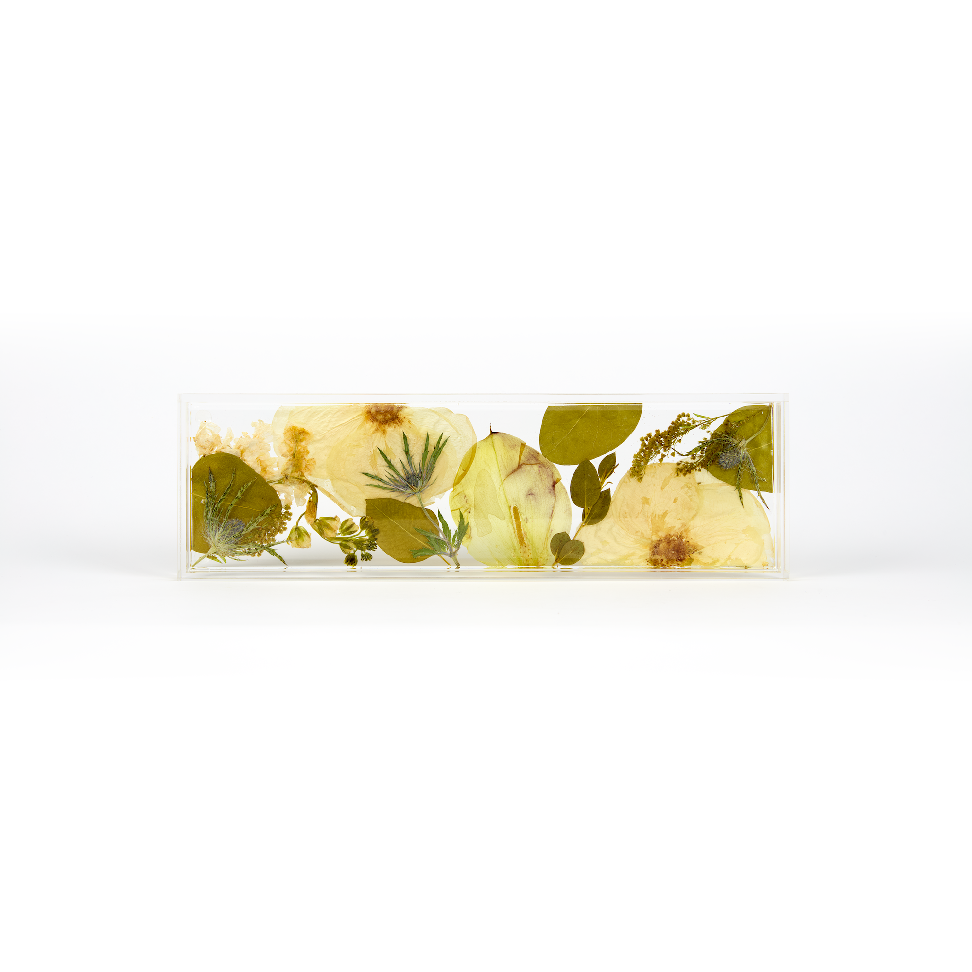 A delicate design of white and green pressed florals in a resin display tray as a part of a wedding bouquet preservation order.
