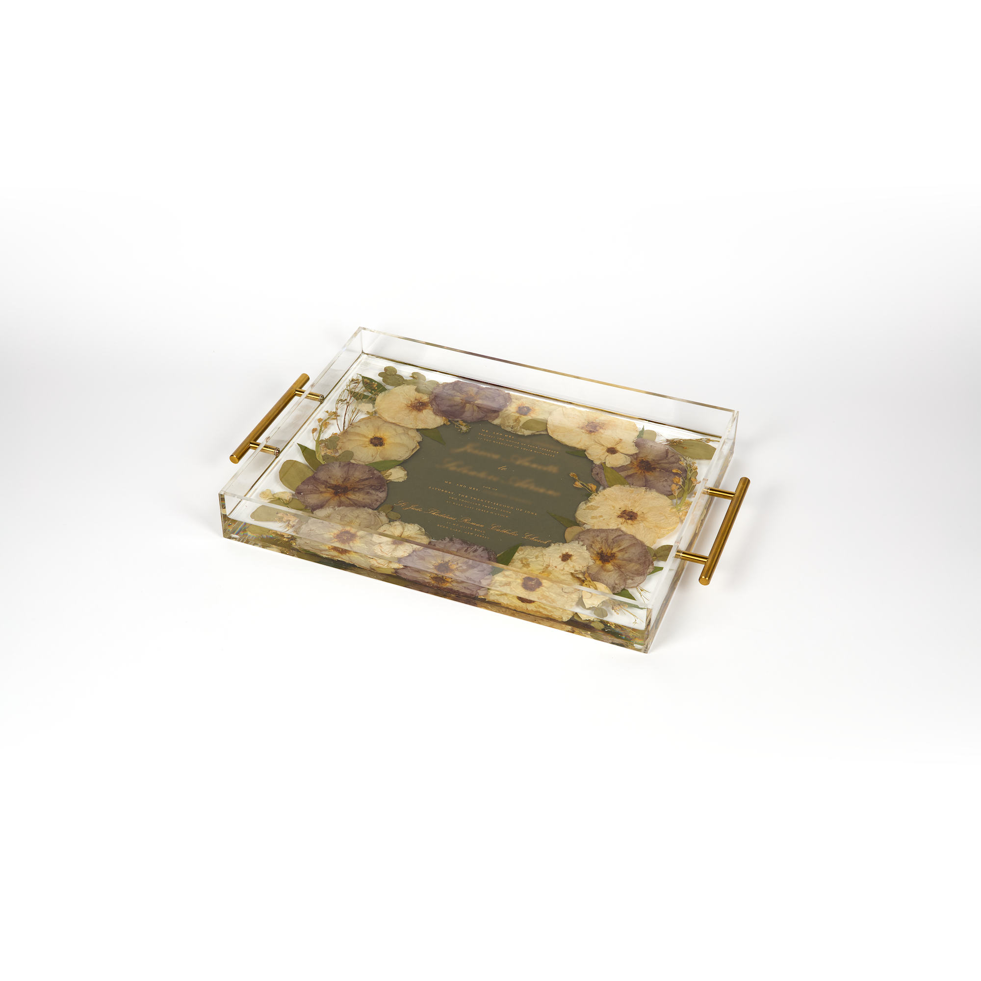 A pressed flower resin serving tray with neutral white and purple colored pressed florals with an invitation in the center. Wedding bouquet preservation as functional home decor.