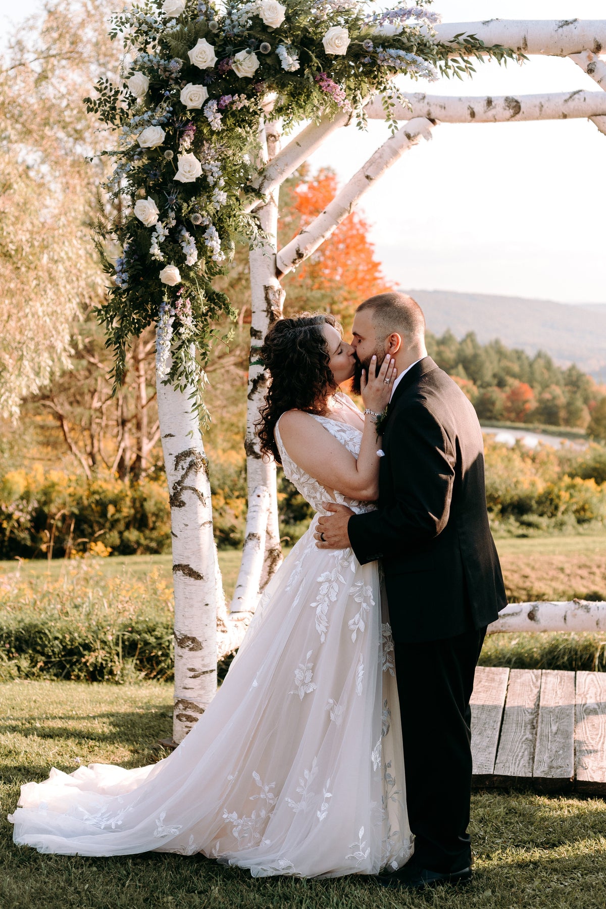 a bride and groom kissing under an altar filled with florals outside