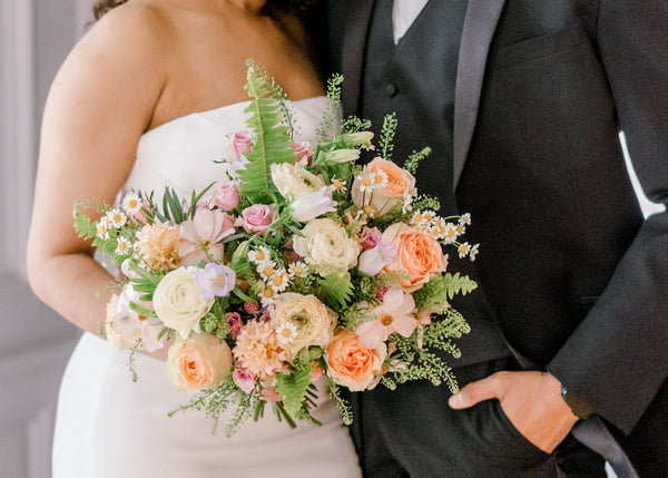 a bride and groom holding a colorful fresh bouquet