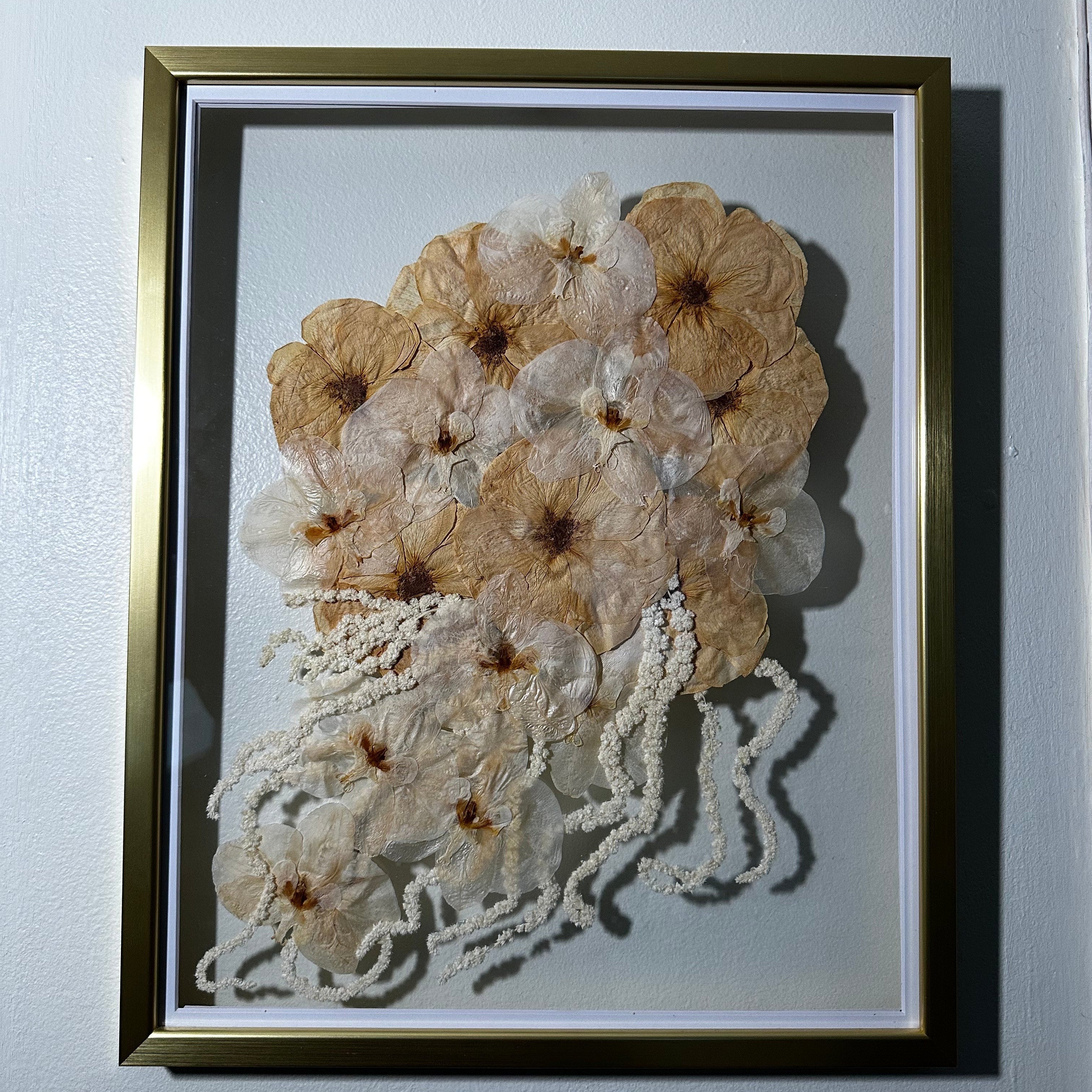 A large gold wood frame with preserved white flowers