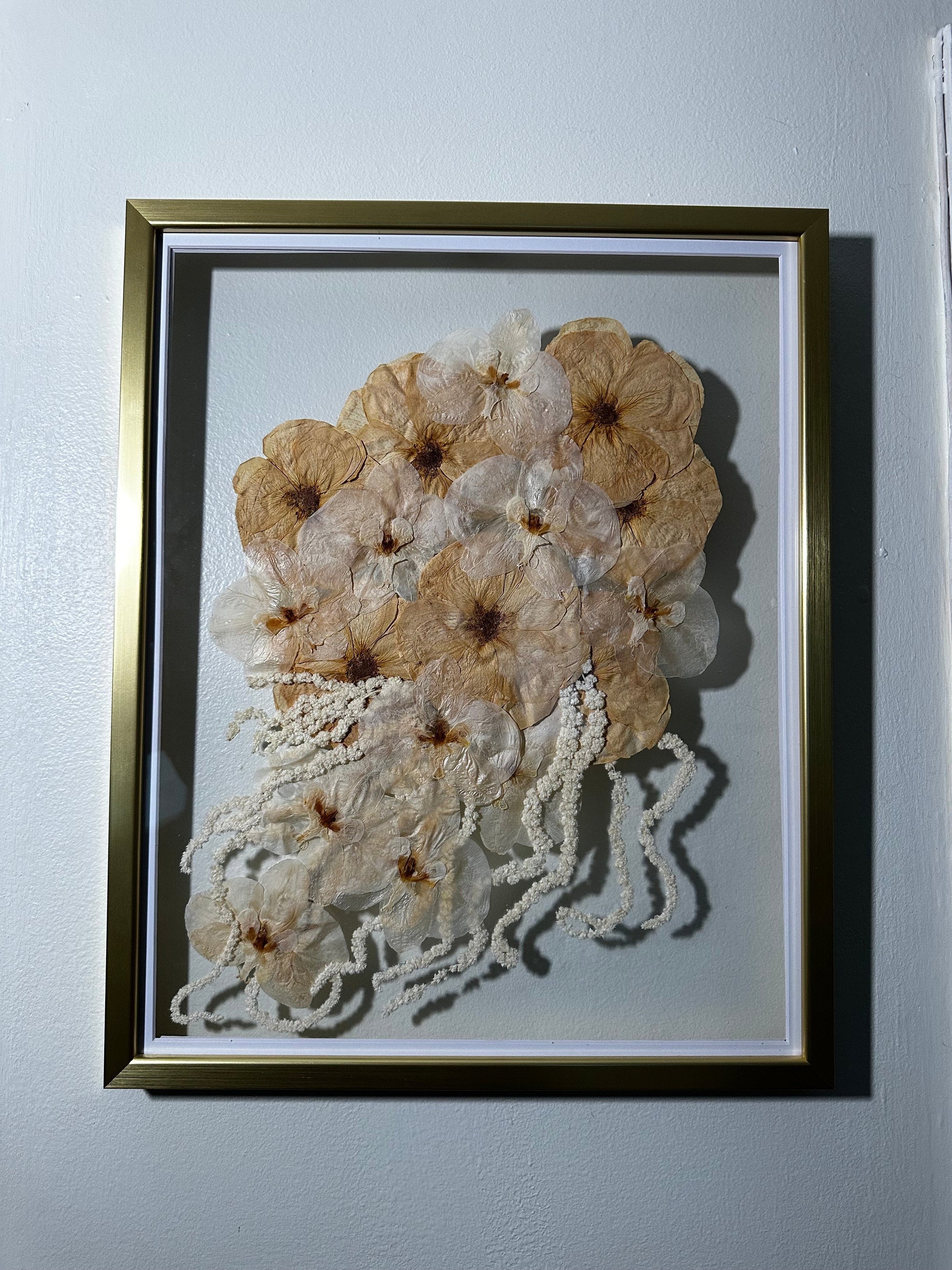 A large gold wood frame with preserved white flowers