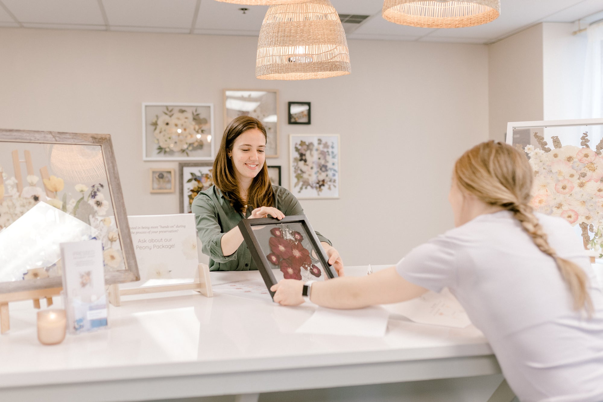 Nikole showing a pressed flower black frame to a client during an in-person consultation appointment.