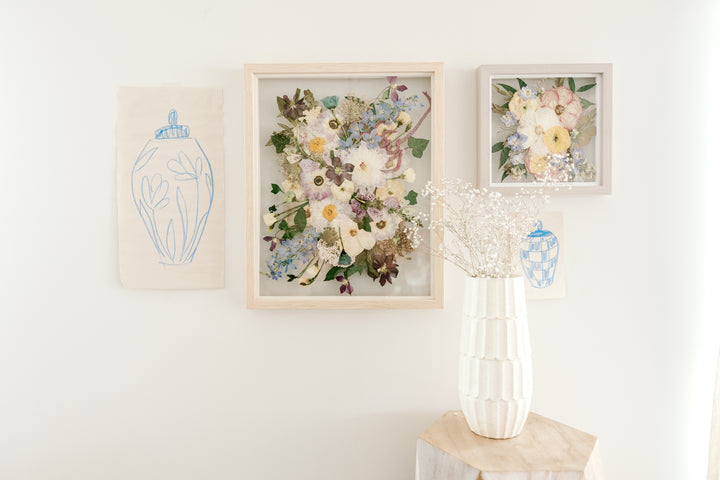 A gallery wall of pressed flower frames hung on display in a home surrounding by other objects.