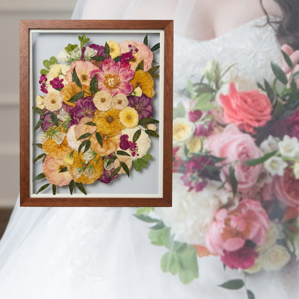 Framed arrangement of pressed flowers with a close-up of a bouquet in the background.