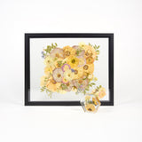 A preservation package featuring a black bouquet frame and a pressed flower ring dish with pink, purple, and coral flowers. 