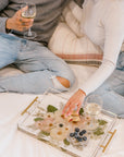 A couple happily uses their pressed floral serving tray while sitting on their bed.