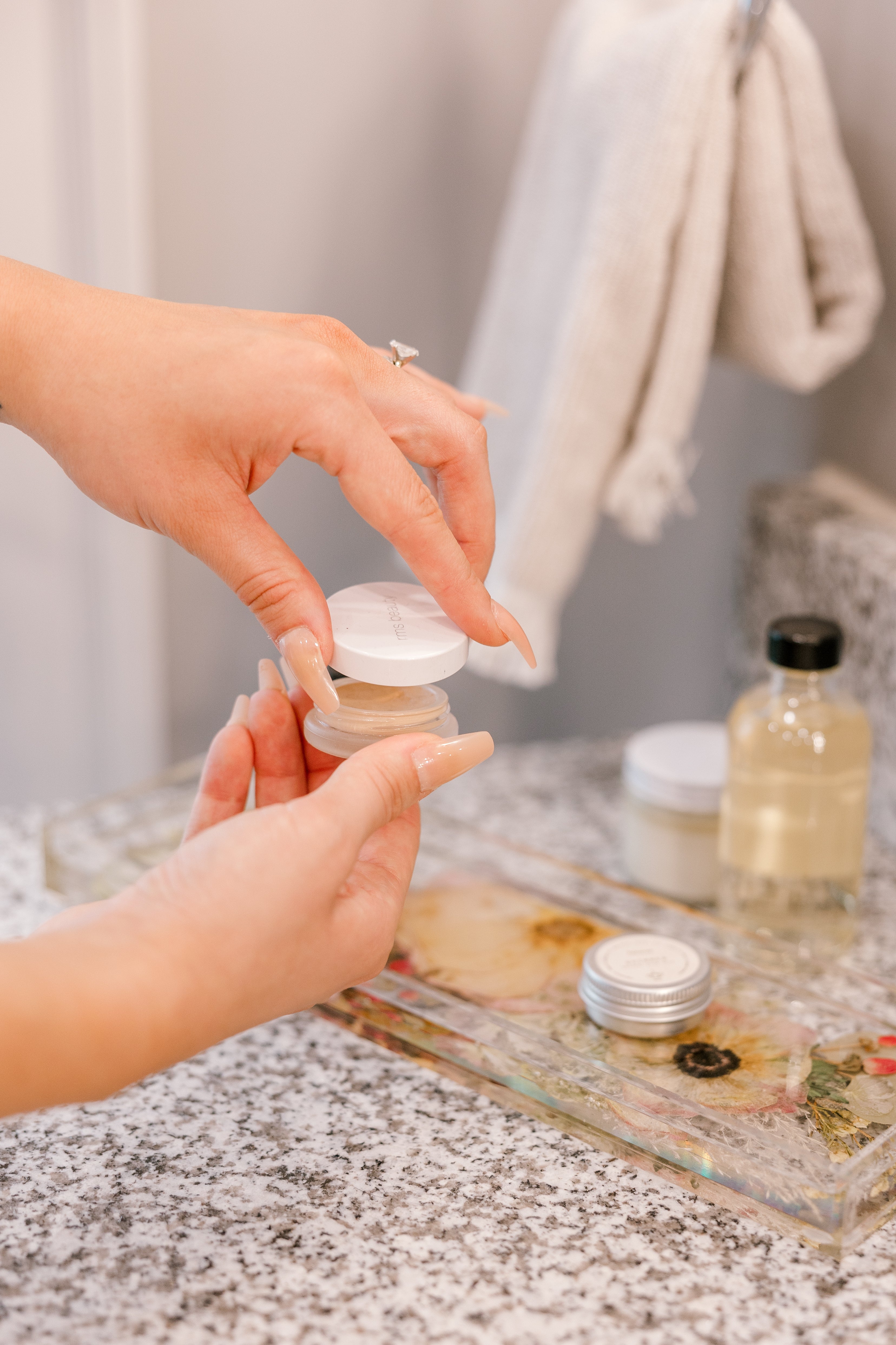 A pressed flower display tray is used as a dish to hold powder room beauty supplies while a woman prepares for the day.