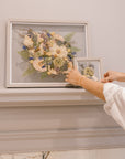 Two grey wood pressed floral frames are displayed on a mantle to be showcased in their home.