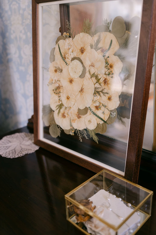 A walnut wood 16x20 pressed floral frame sets against a mirror