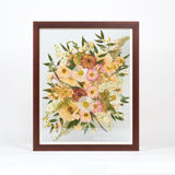 A large pressed floral bouquet encased in a brown frame with a date written in white script