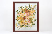 A large pressed floral bouquet encased in a brown frame with a date written in white script