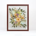 Colorful pressed flowers encased in a brown frame