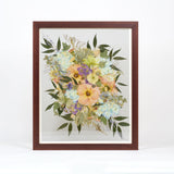 Colorful pressed flowers encased in a brown frame