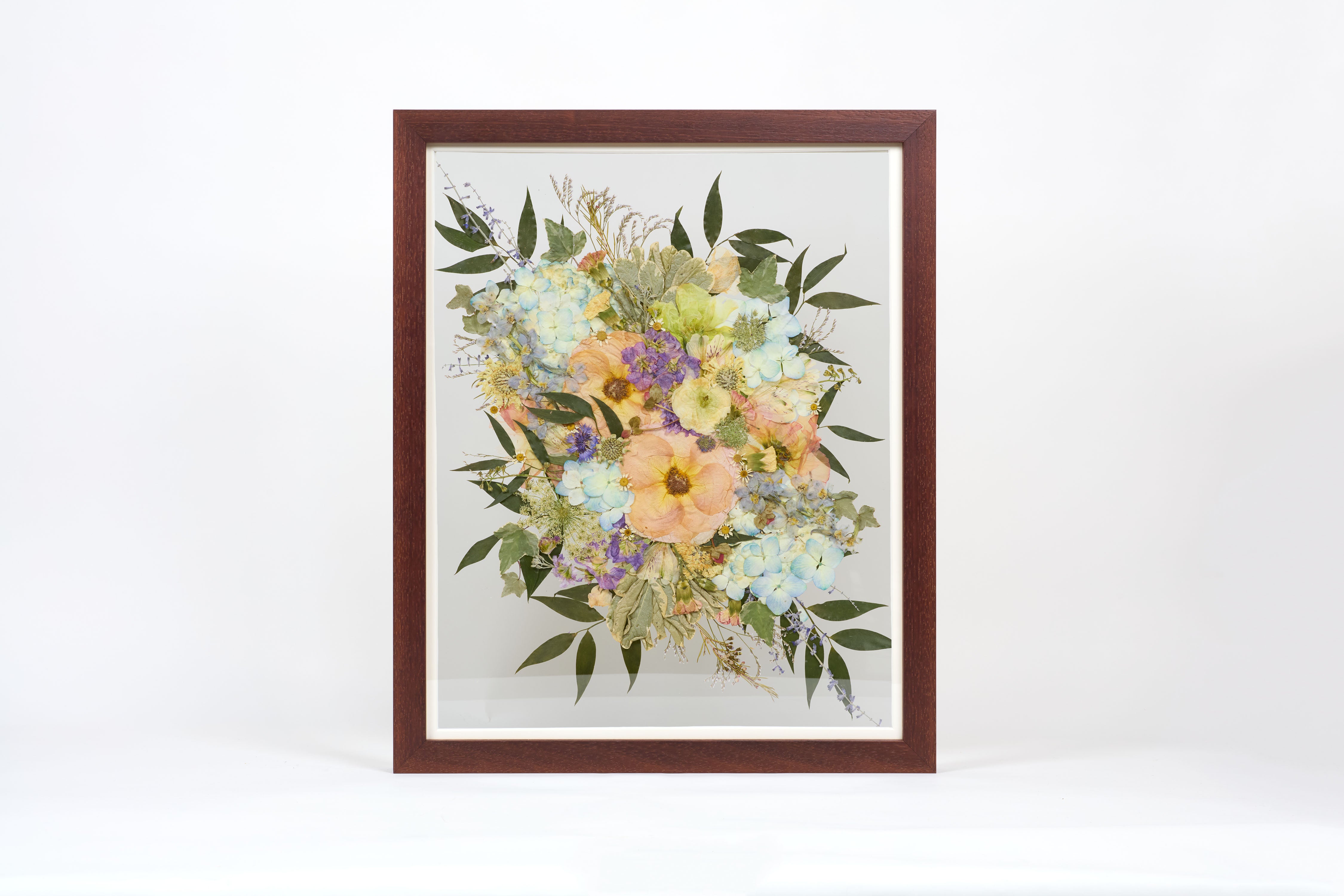 Colorful pressed flowers encased in a brown frame