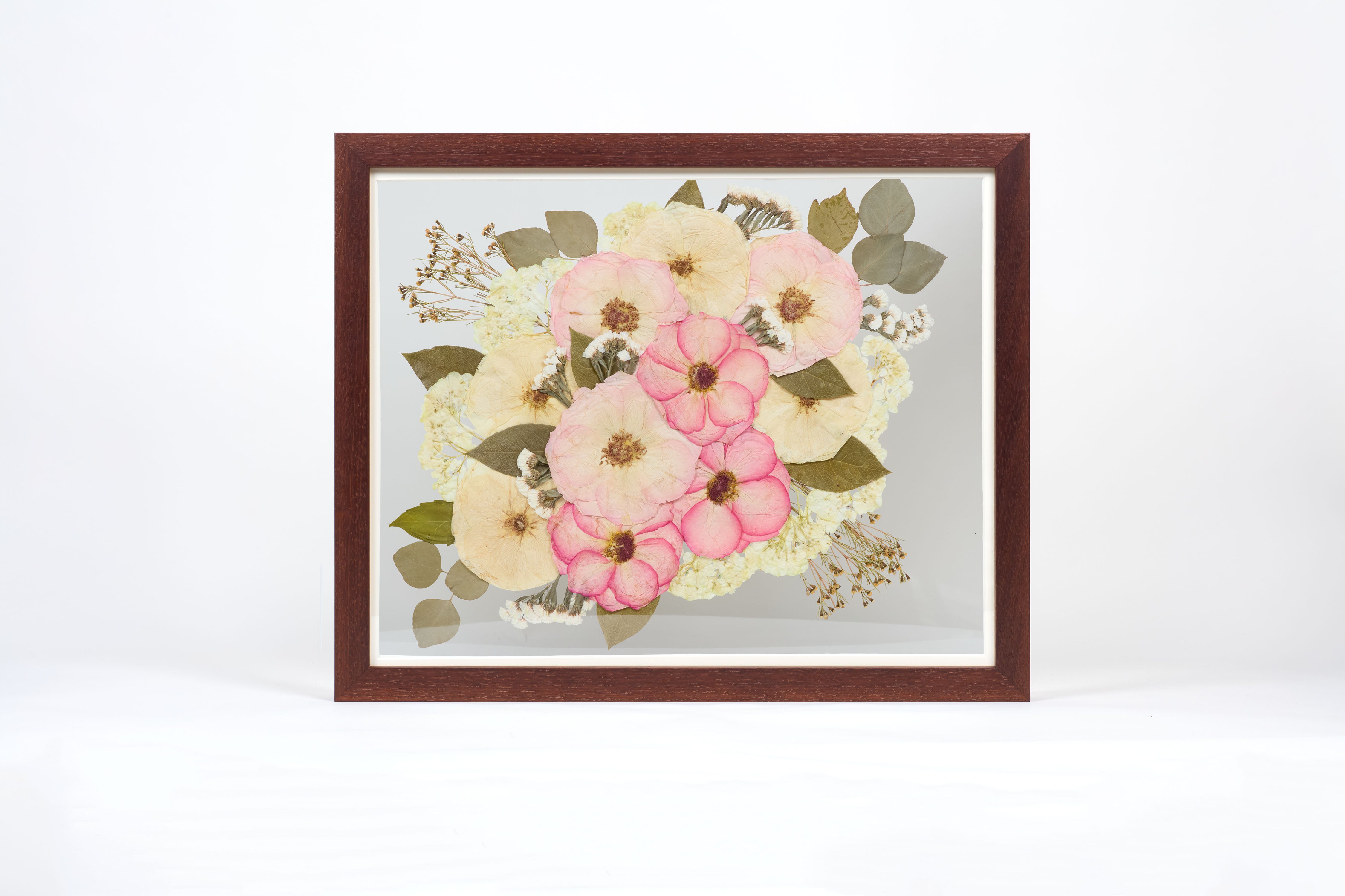 a large walnut colored frame with pink and white pressed florals