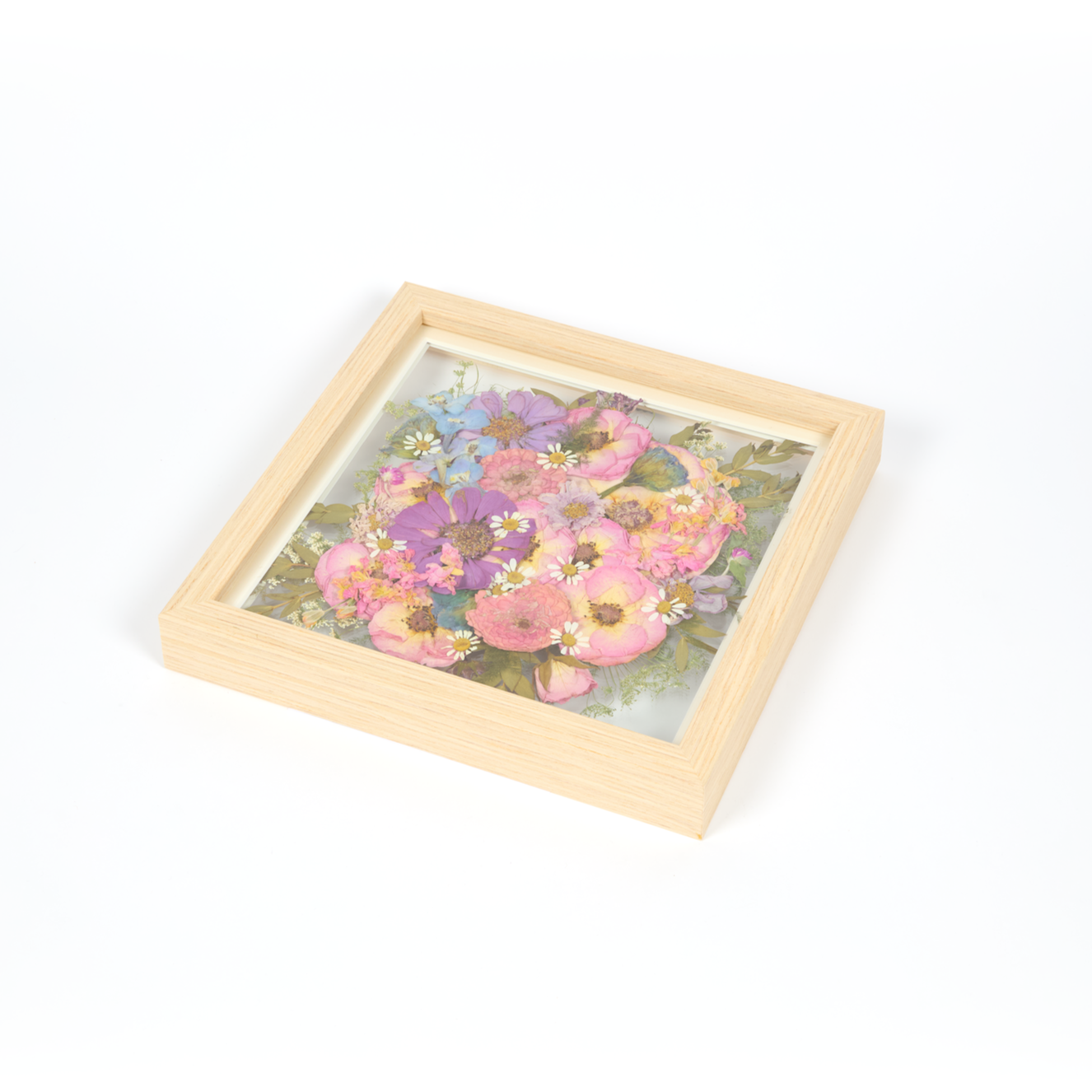 Wedding bouquet preservation frame in a 10x10 size with natural wood surround. All bright pink, blue, and purple pressed florals featuring burst design style.