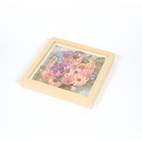 Wedding bouquet preservation frame in a 10x10 size with natural wood surround. All bright pink, blue, and purple pressed florals featuring burst design style.