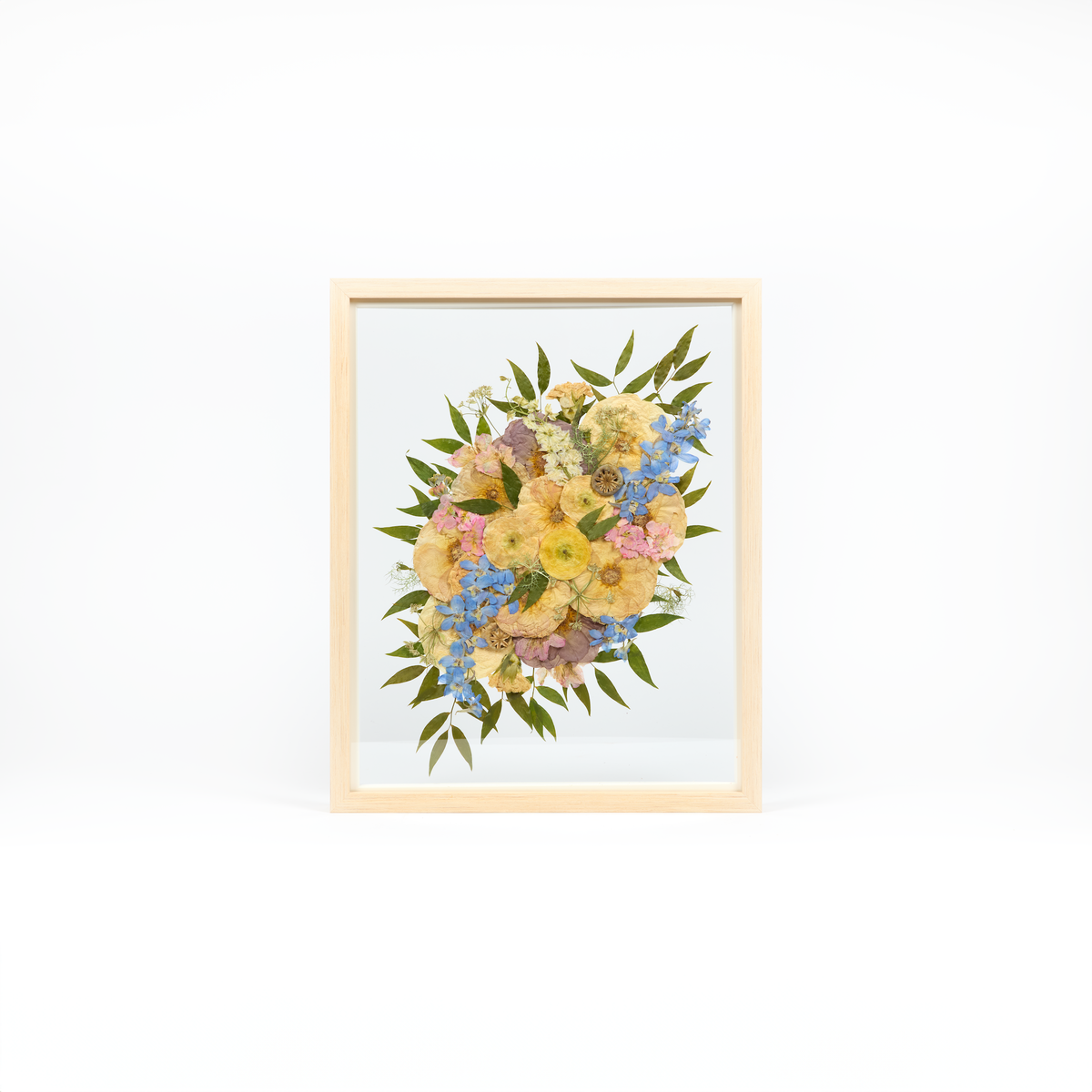 Bridal bouquet preservation in a 16x20 natural wood frame. Yellow, pink, and blue pressed florals fill the frame with a floating glass background. 