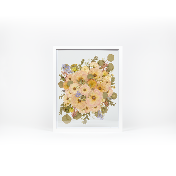 A pressed bridal bouquet in a white wood floating frame featuring pressed pink, coral, and white florals. 