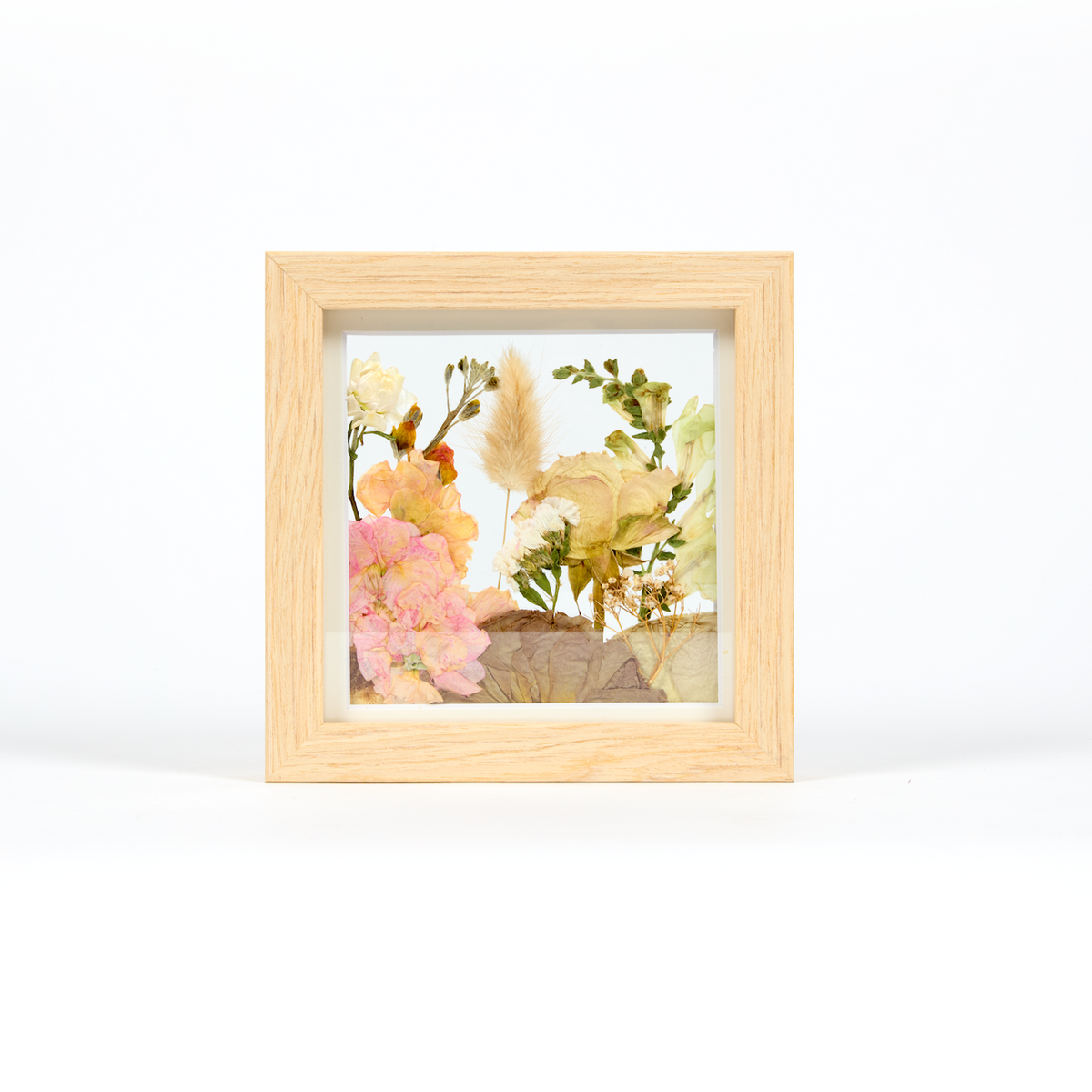 Small flower preservation frame with pink, yellow, and green flowers. 6x6 inch display in a natural wood frame in our field style design.