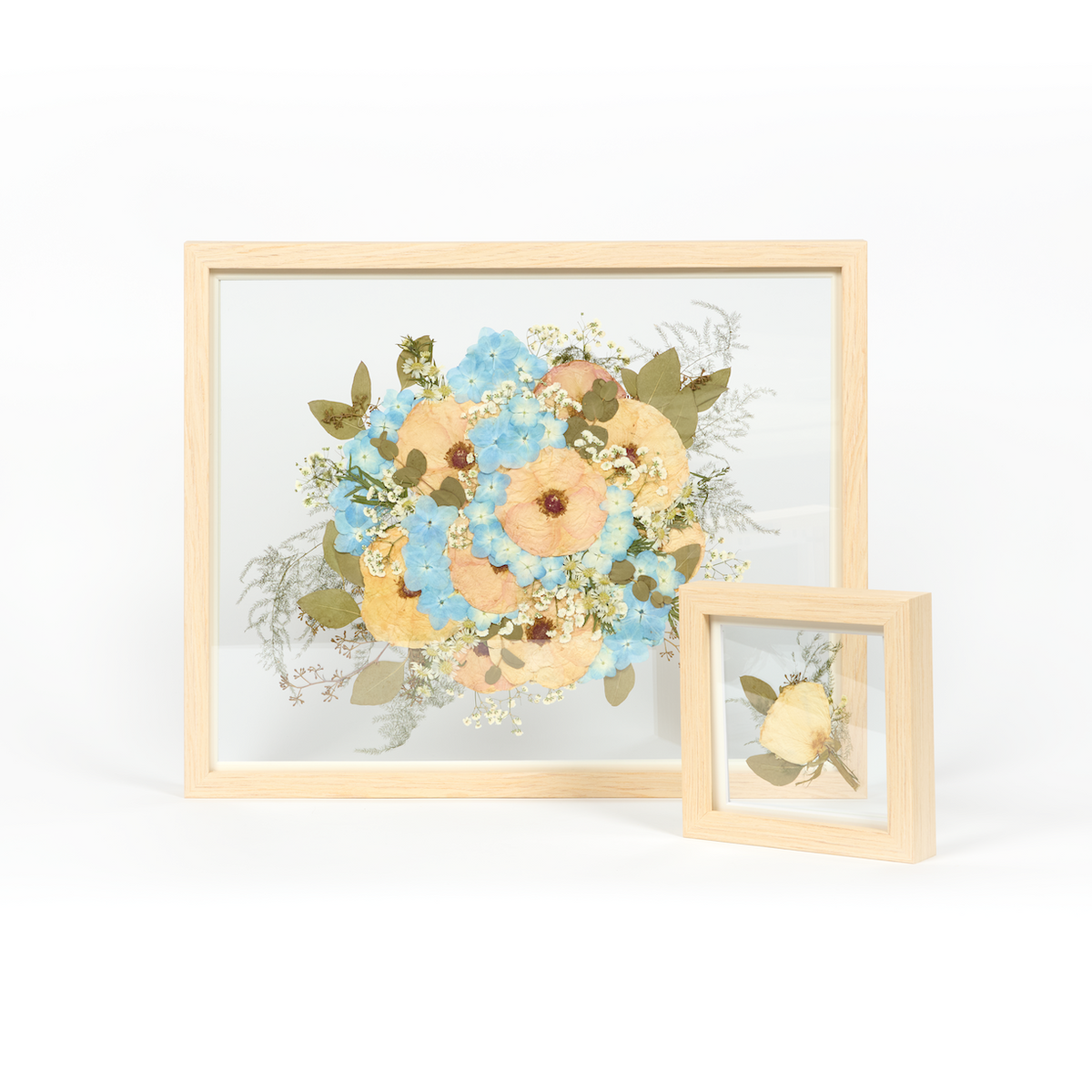 A wedding bouquet preservation frame set with white and blue pressed florals and pressed greenery.  