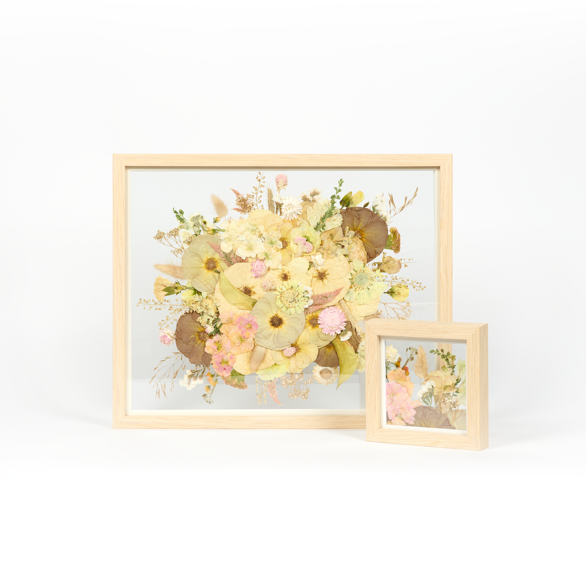 Wedding bouquet preservation frames in natural wood featuring light pink and white pressed florals in a 16x20 and a 6x6 frame. 