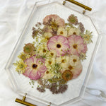 A spring-toned wedding bouquet preserved in a resin serving tray with gold handles.