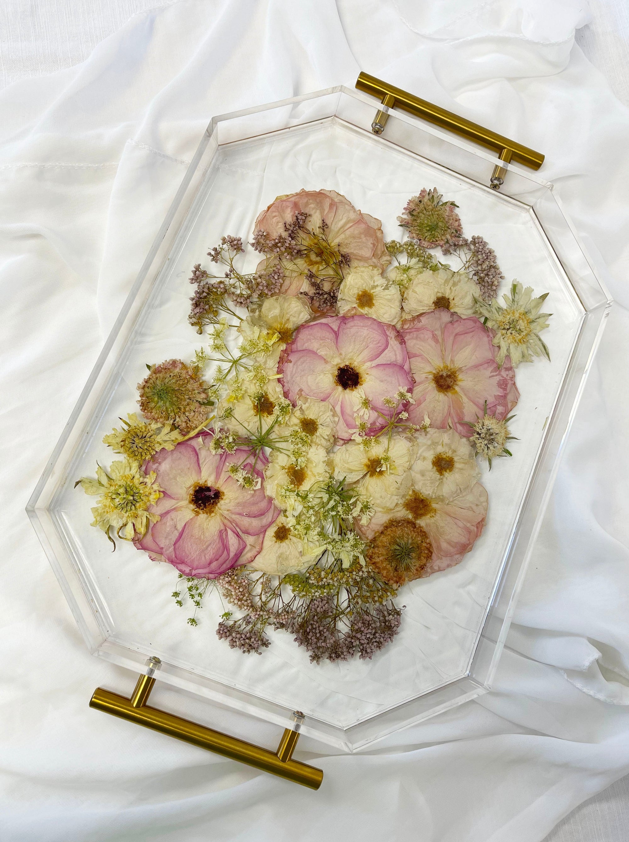 A spring-toned wedding bouquet preserved in a resin serving tray with gold handles.