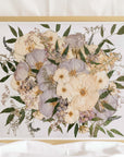 A pressed flower bouquet preserved in a glass frame with a gold wood surround, made by Element Preservation (Element Design Co.)