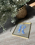 square gold hanging frame with blue pressed flowers. 