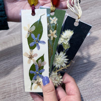 Hands holding three bookmarks that have preserved flowers inside