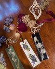 A wooden table that has string, pressed flowers, and bookmarks on top