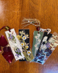 Seven bookmarks laid on a table made with a pressed floral design