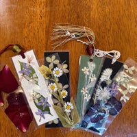 Seven bookmarks laid on a table made with a pressed floral design