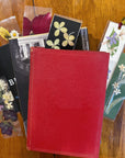 Books stacked on top of each other on a table with floral bookmarks surrounding them