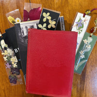 Books stacked on top of each other on a table with floral bookmarks surrounding them