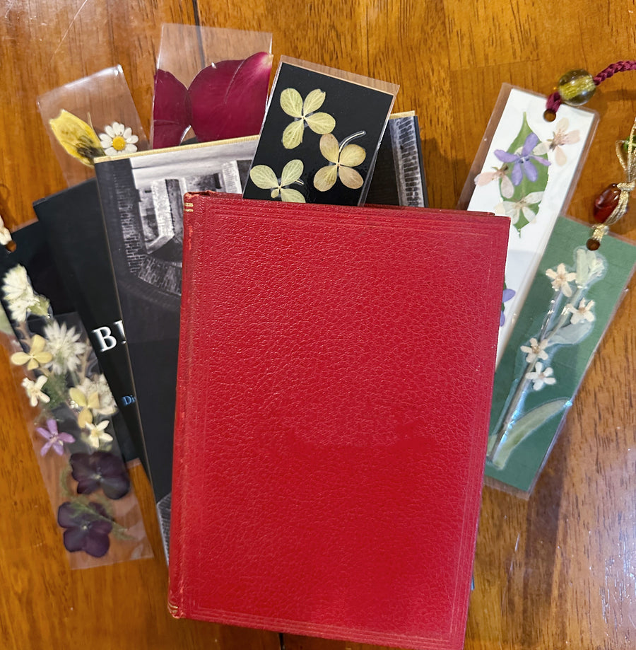 Books stacked on top of each other on a table with floral bookmarks surrounding them