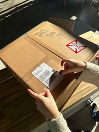 A woman puts a shipping label on her bouquet box before she sends it off to be preserved.