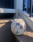 pressed flowers attached to a white pumpkin on the side of the stairs outside a house